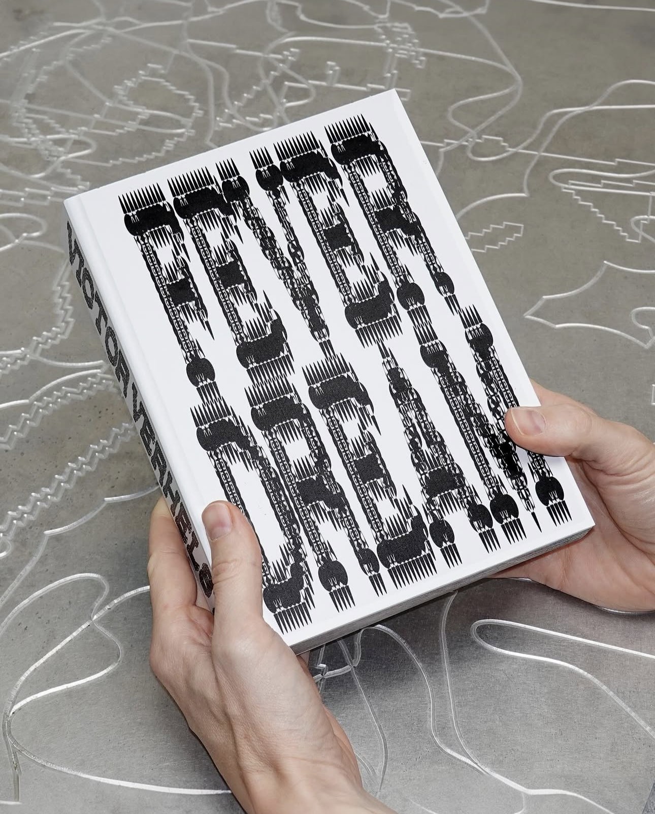 Book with a distorted black typographic cover held in two hands