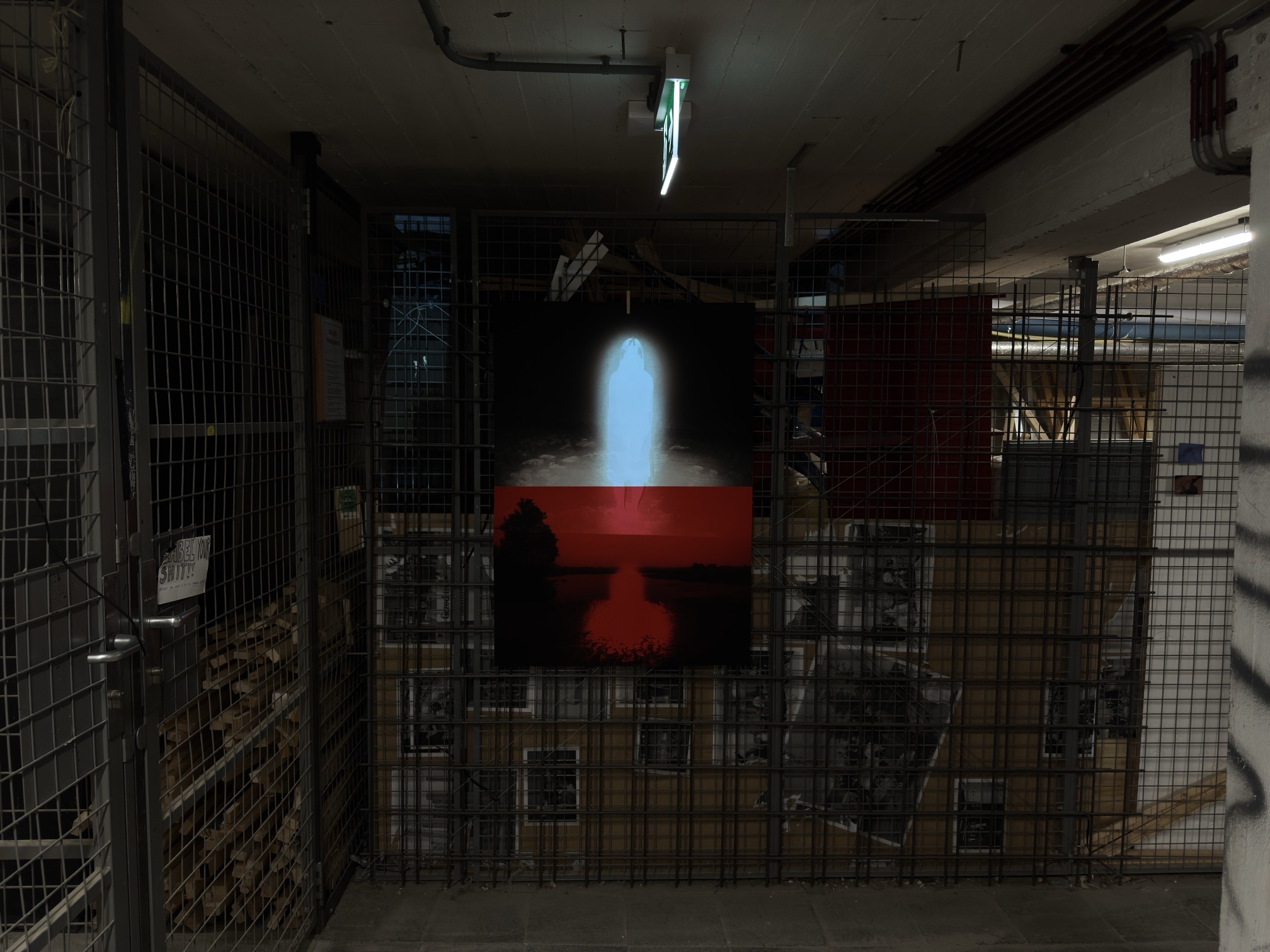 Red and blue poster hanging on a wire mesh wall in a dark basement