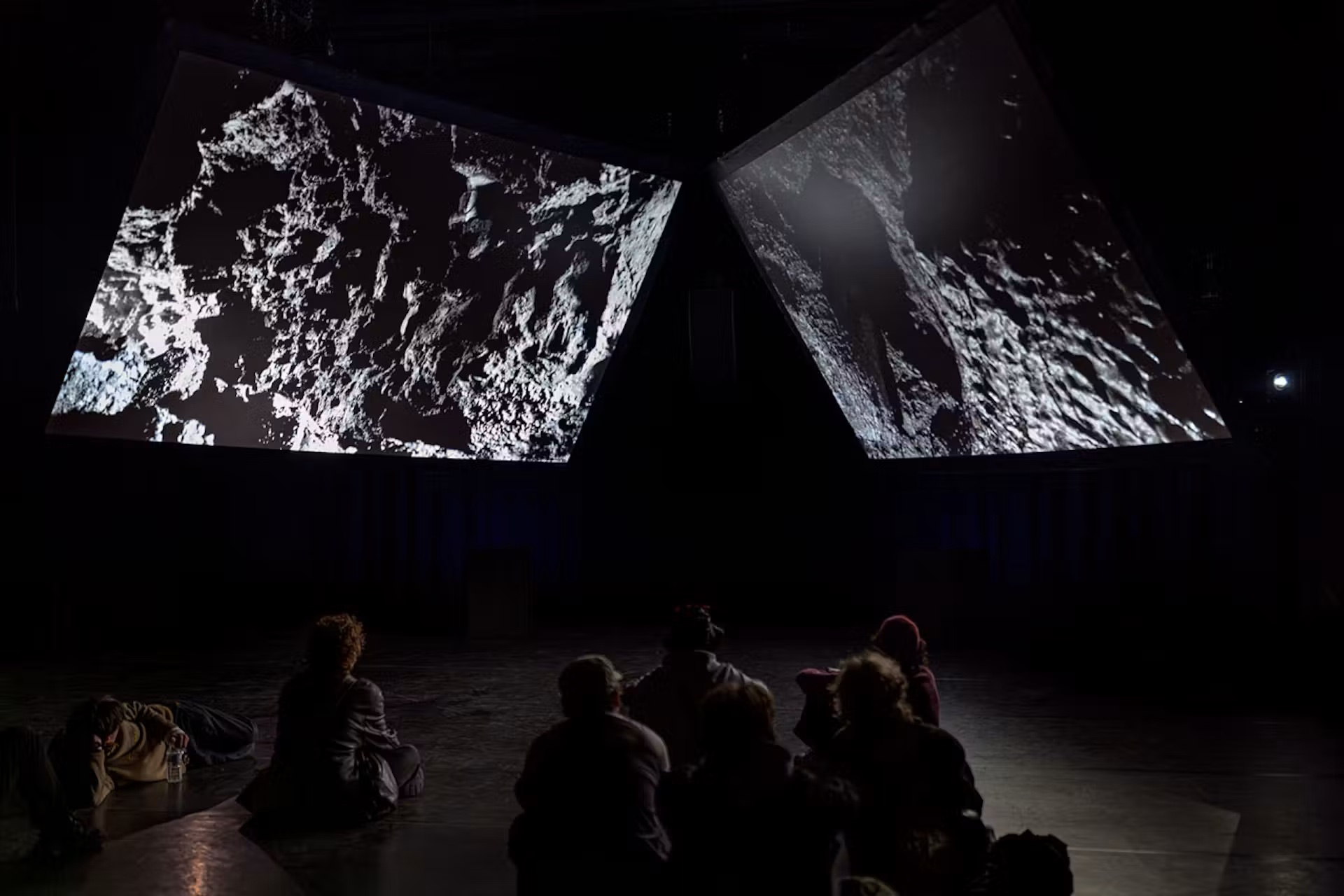 Audience watching two large projections of rocky surfaces