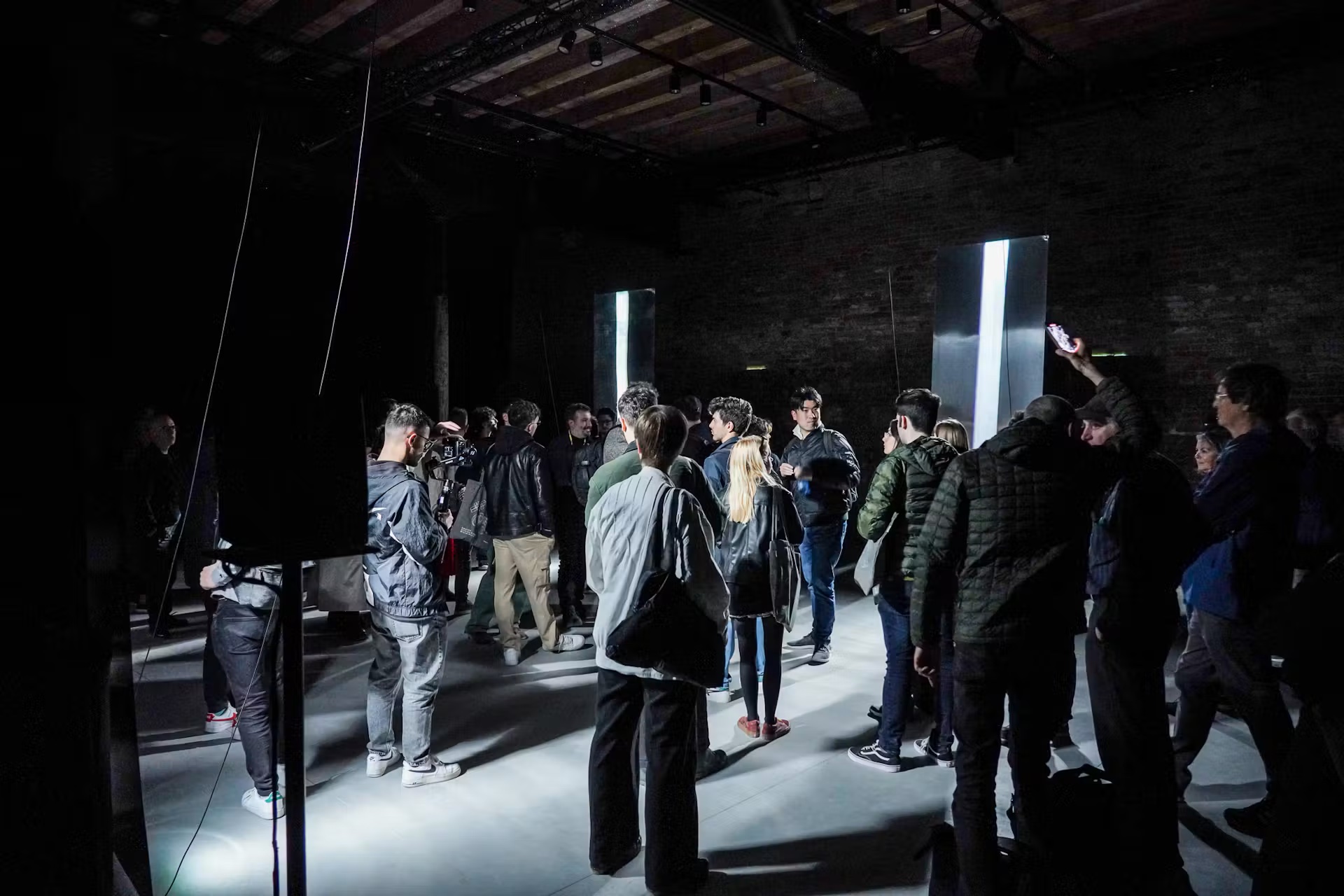 Visitors in a dark hall with light installations
