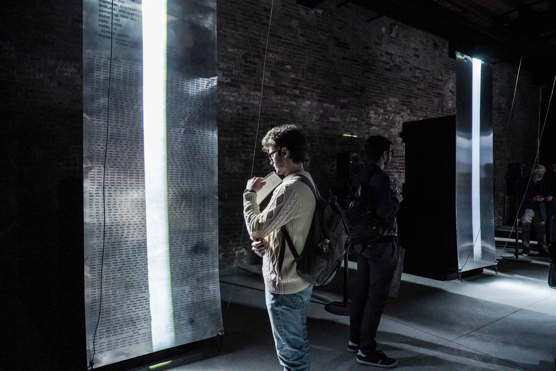 Visitor reading a data print beside a light installation