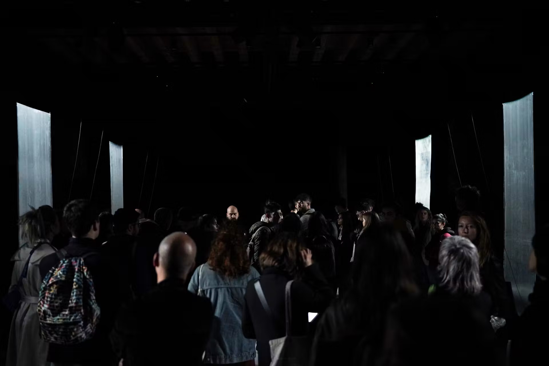 Crowd in a dark hall between glowing panels