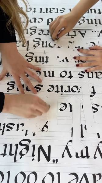 Students working on large blackletter lettering on paper