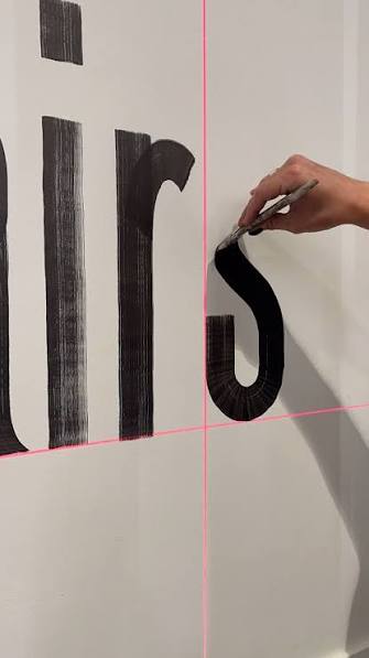 Painting a letter on a wall along laser guide lines